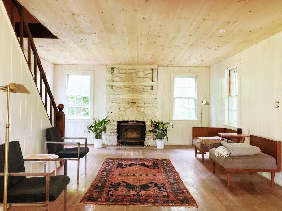 sala de estar con chimenea, mesa y sillas en Mountain Farmhouse (The Lorca, Catskills), en Shandaken