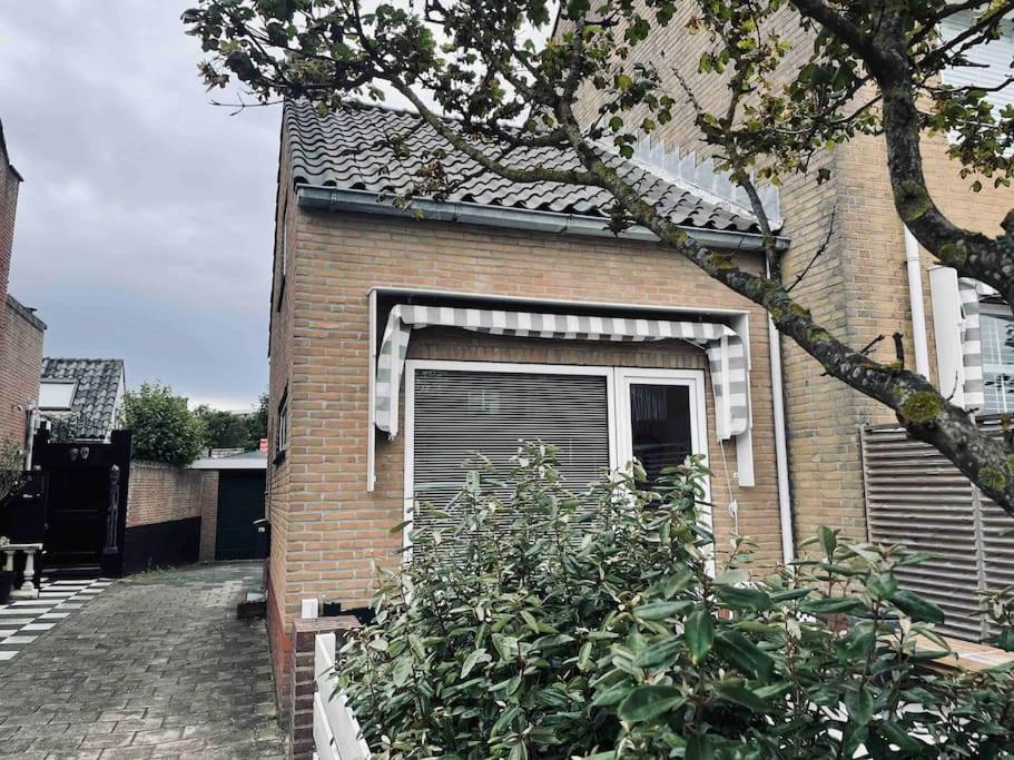 een stenen huis met een raam met een luik bij Tiny beachhouse - free parking in Noordwijk