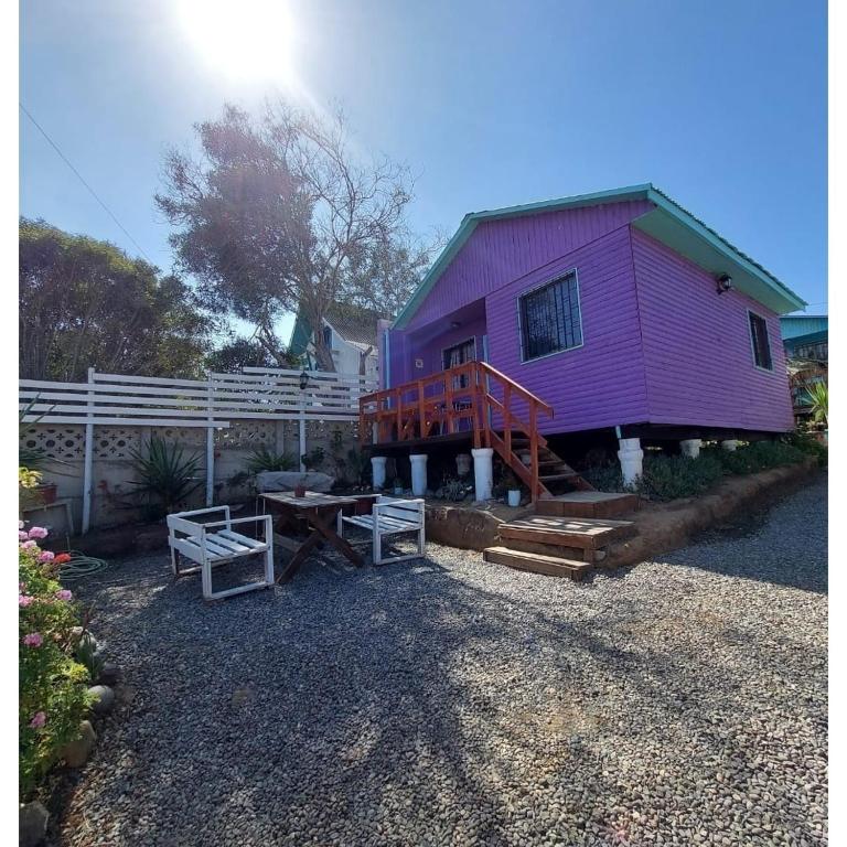 ein lila Haus mit einem Picknicktisch davor in der Unterkunft Cabañas Polymar el Tabo in El Tabo