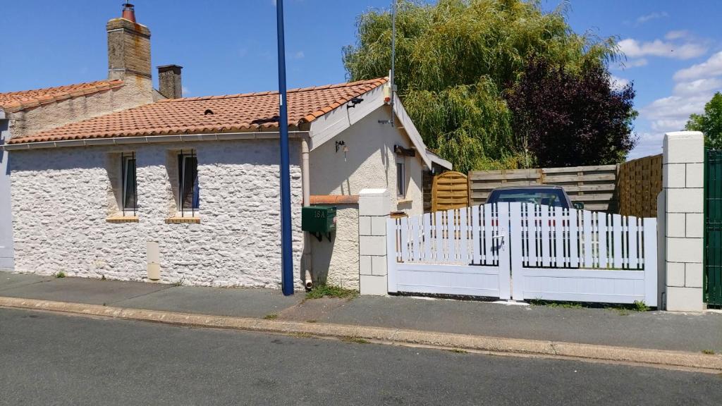 une clôture blanche devant une maison blanche dans l'établissement Maison de vacances - Locagrues 18A, à Grues
