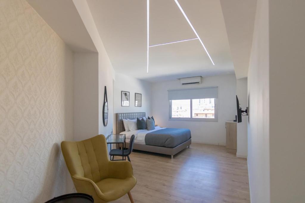 een slaapkamer met een bed en een stoel bij Phaedrus Living: Plateia Suite Grigio in Nicosia
