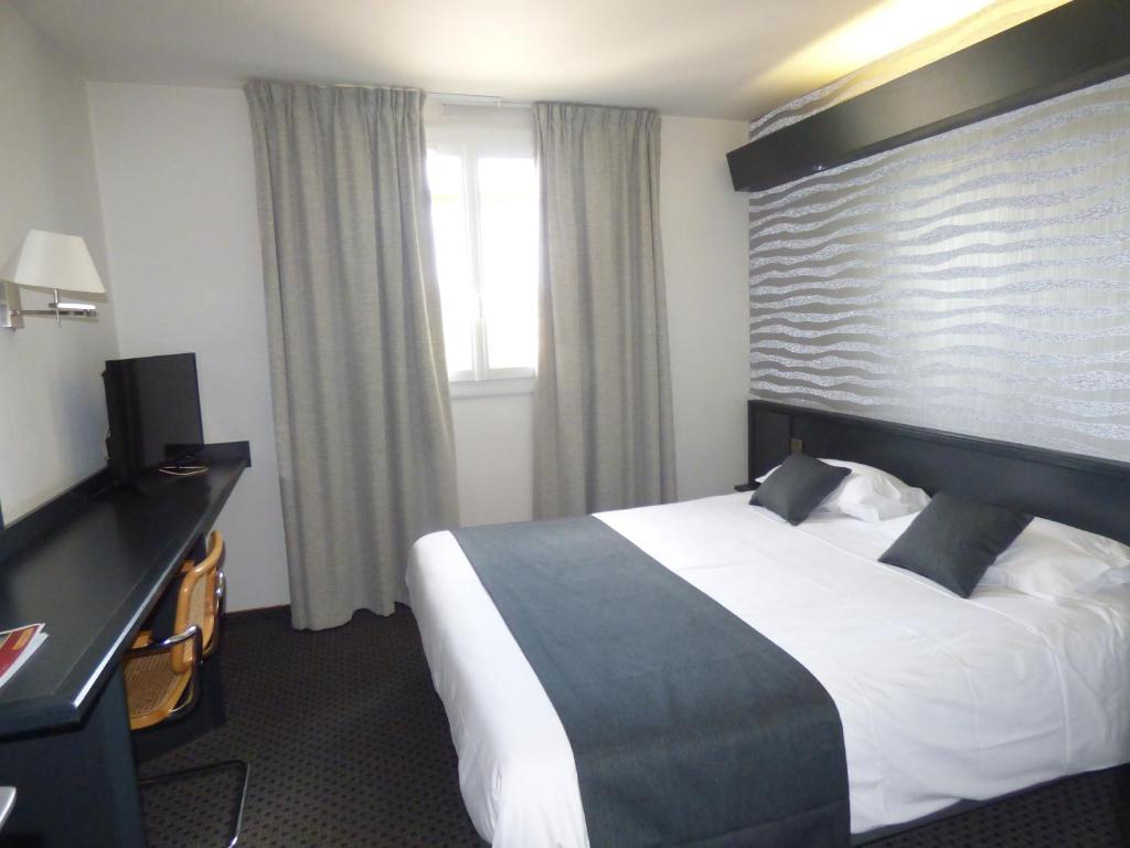 a hotel room with a bed and a desk at Brit Hotel Confort Villefranche-de-Rouergue in Villefranche-de-Rouergue