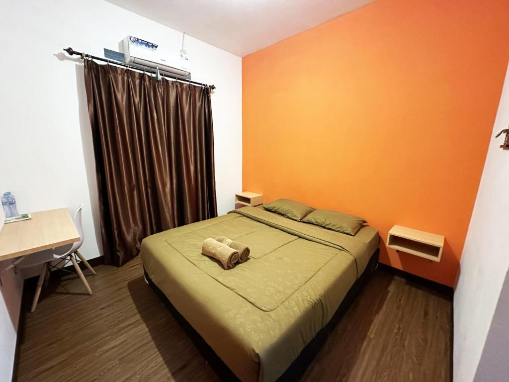 1 dormitorio con 1 cama con pared de color naranja en Casa Feby Guest House, en Bandung
