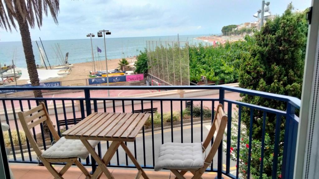 a table and chairs on a balcony with the beach at Beachfront Apartment with Sea Views & Private Parking in San Pol de Mar