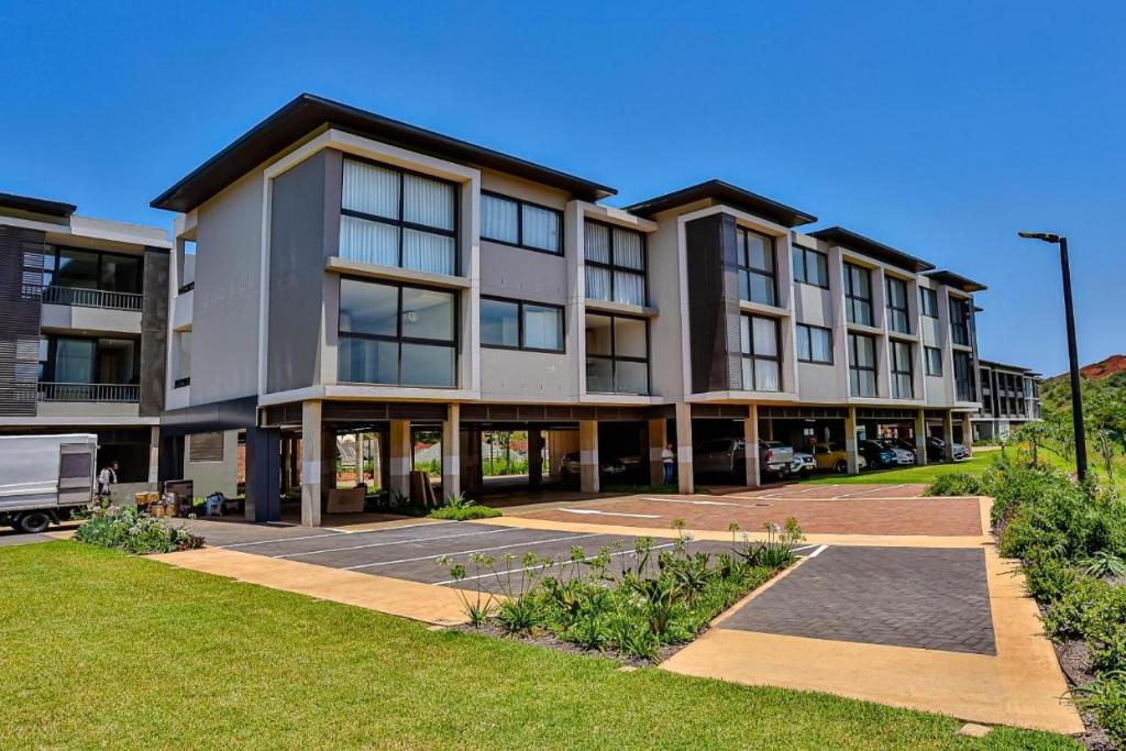 a large apartment building with a parking lot at Zimbali Lakes Boulevard Suites Studio Apartments in Ballito