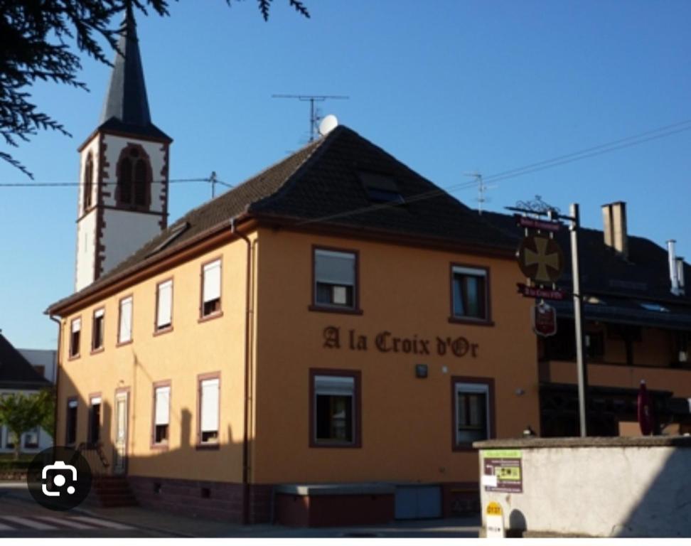 un bâtiment avec une tour d'horloge et une église dans l'établissement Hôtel restaurant à la croix d'or, à Sessenheim