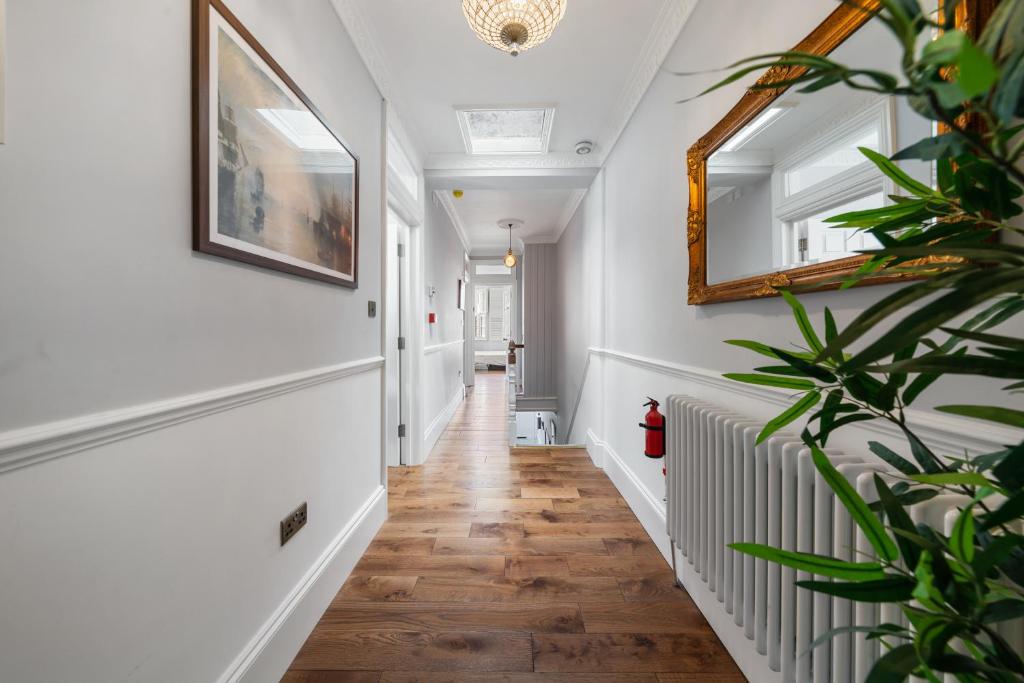 Hotel Royal Greenwich Hospitality, a hallway with white walls and wood floors and a mirror at Royal Greenwich Hospitality in London