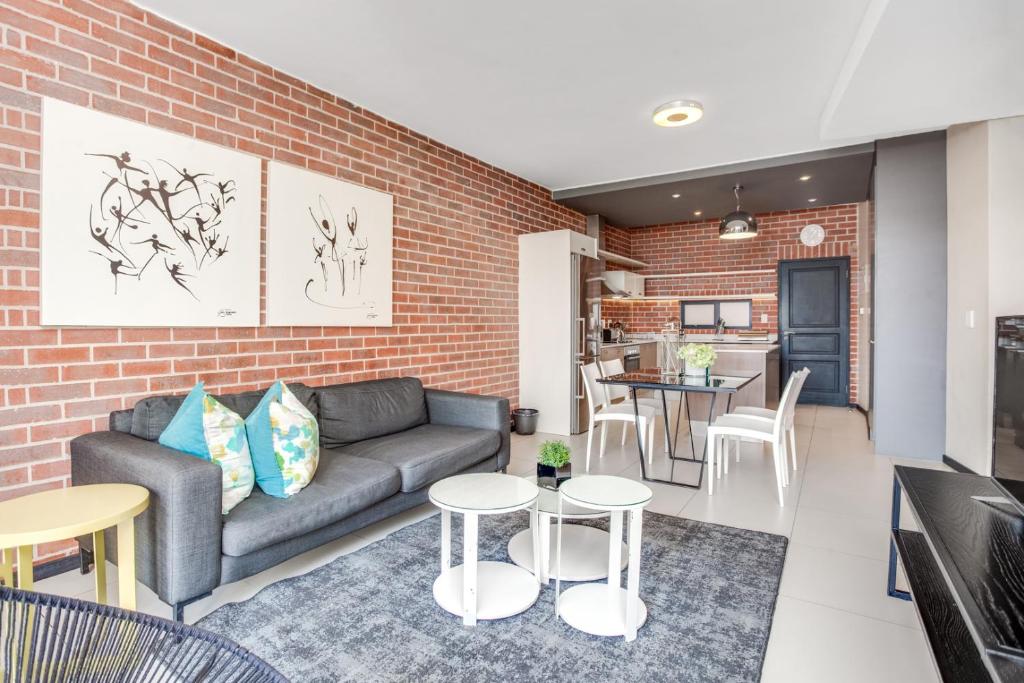 a living room with a couch and a brick wall at Urban Oasis Apartments at The Vantage in Johannesburg