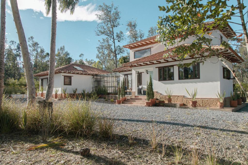 a white house with trees and a gravel driveway at Casa Dino en Villa de Leyva in Villa de Leyva