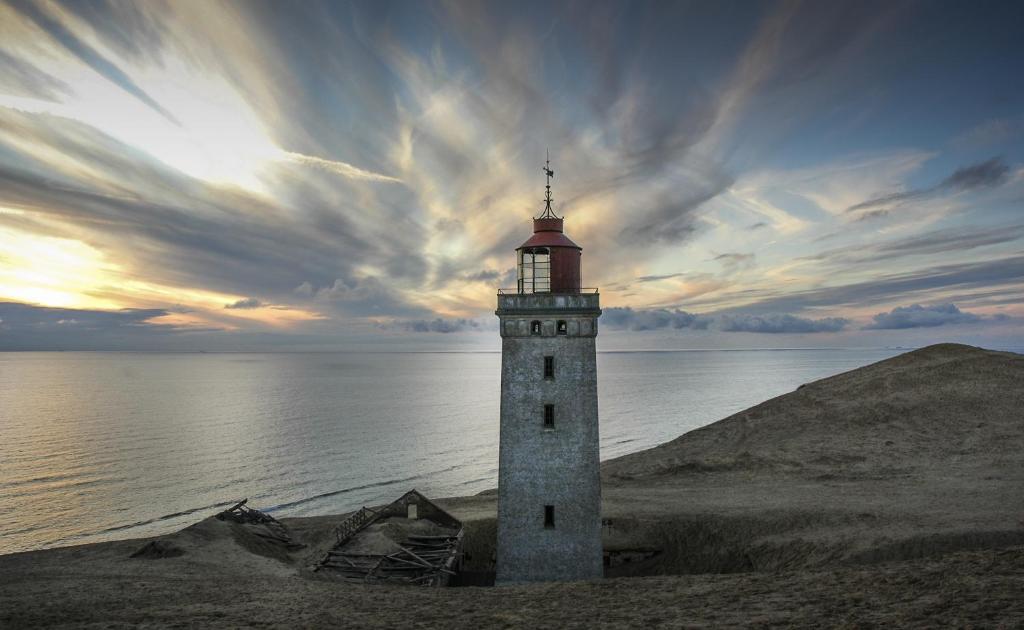 a lighthouse on the shore of a body of water at Hotel Kirkedal B&B in Lønstrup