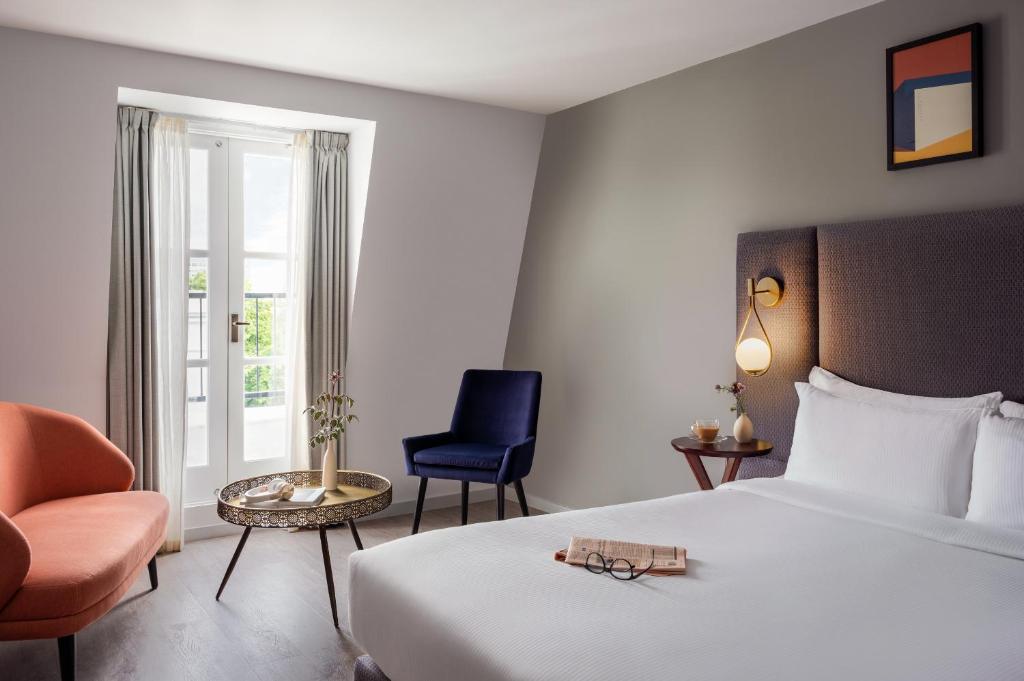 ein Hotelzimmer mit einem Bett und einem Stuhl in der Unterkunft Sonder The Henry in London