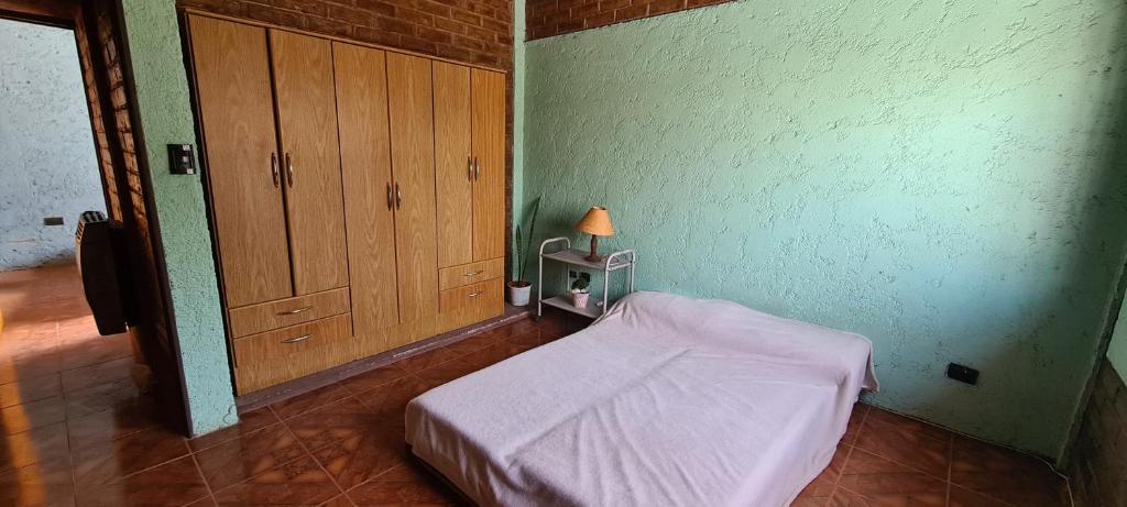 a small bedroom with a bed and a lamp on a table at Posada La Campiña in Ciudad Lujan de Cuyo