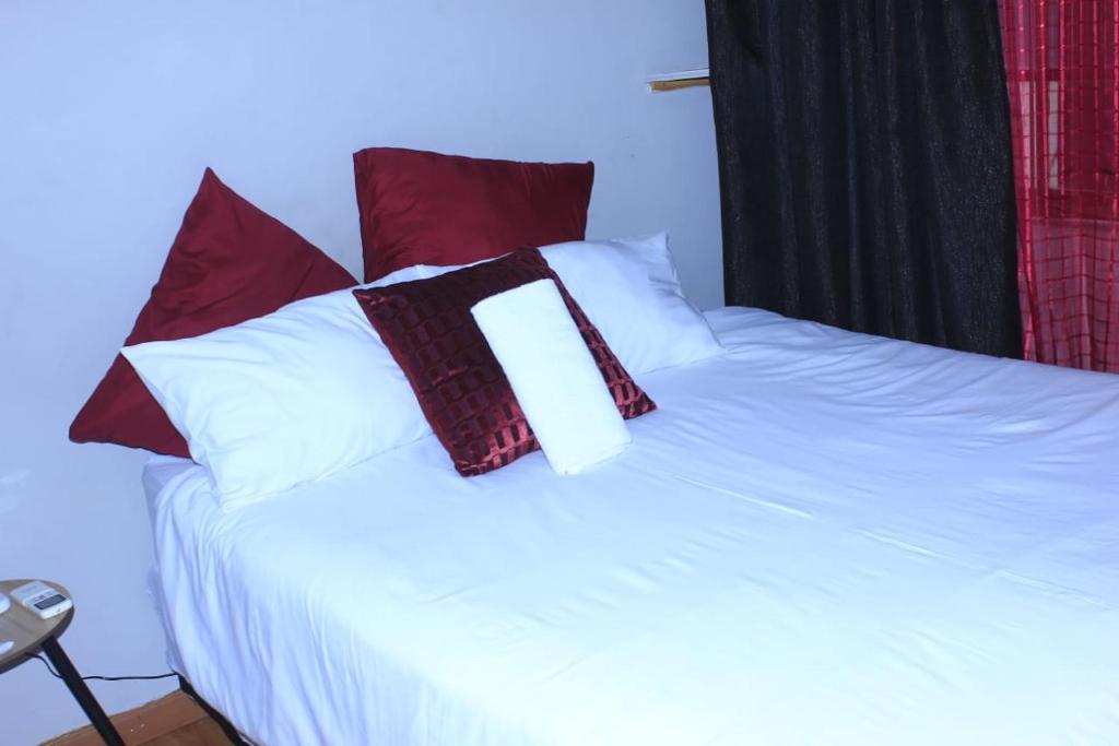a white bed with red and white pillows on it at Sun & Night in Empangeni