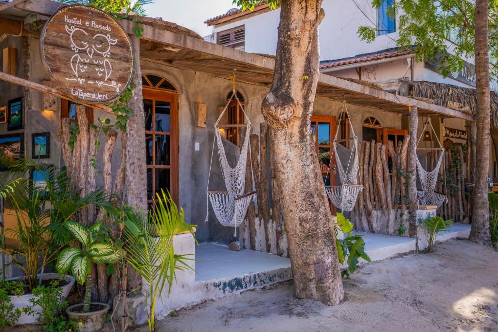 una casa con hamacas en la parte delantera en LaTaperaJeri Hostel, en Jericoacoara