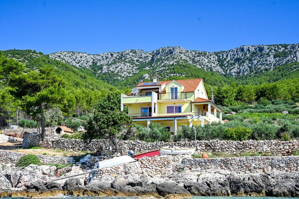 una casa amarilla en una colina junto al agua en Villa Marin - 4 apartments en Zavala