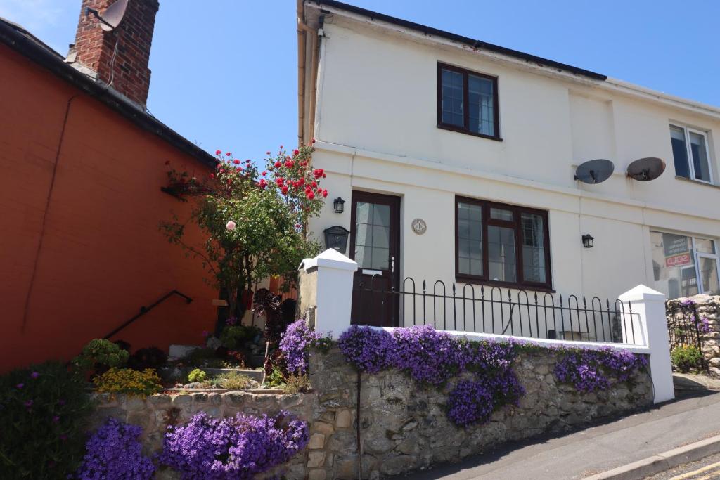 a white house with purple flowers in front of it at 1 Tulse Hill Cottages in Ventnor