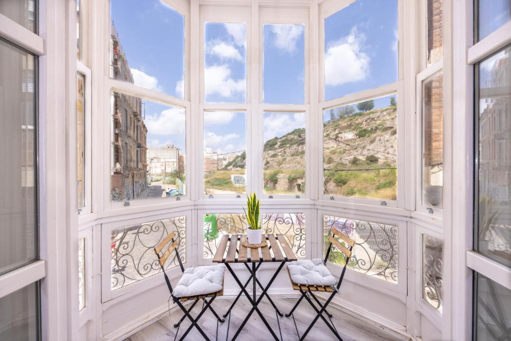 um quarto com uma mesa e cadeiras em frente a uma janela em Apartamentos Turísticos Gran Vía em Cartagena