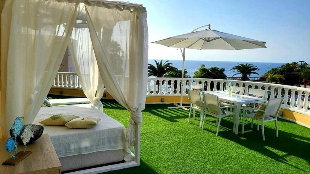 ein Bett und ein Tisch und ein Sonnenschirm auf dem Balkon in der Unterkunft PaulMarie Apartment Gigantes Ocean Lounge in Puerto de Santiago