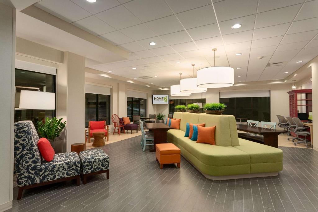 a waiting room with a green couch and chairs at Home2 Suites By Hilton Goldsboro in Goldsboro
