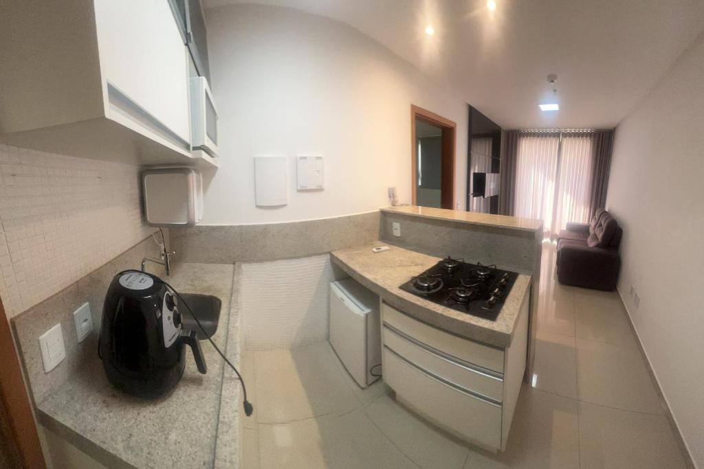 Il comprend une petite cuisine équipée d'une cuisinière et d'un comptoir. dans l'établissement Flat Espetacular no Flamboyant, à Goiânia