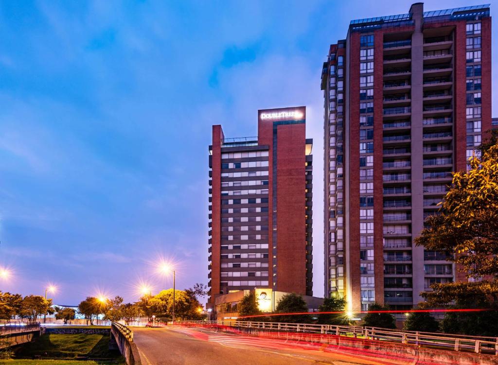 two tall buildings in a city at night at Hilton DoubleTree Bogotá Salitre AR in Bogotá