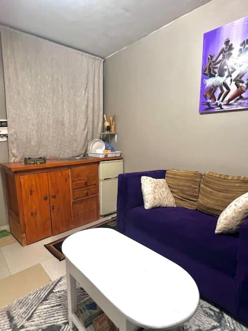 Cozy studio apartment في دار السلام: غرفة معيشة مع أريكة زرقاء وطاولة