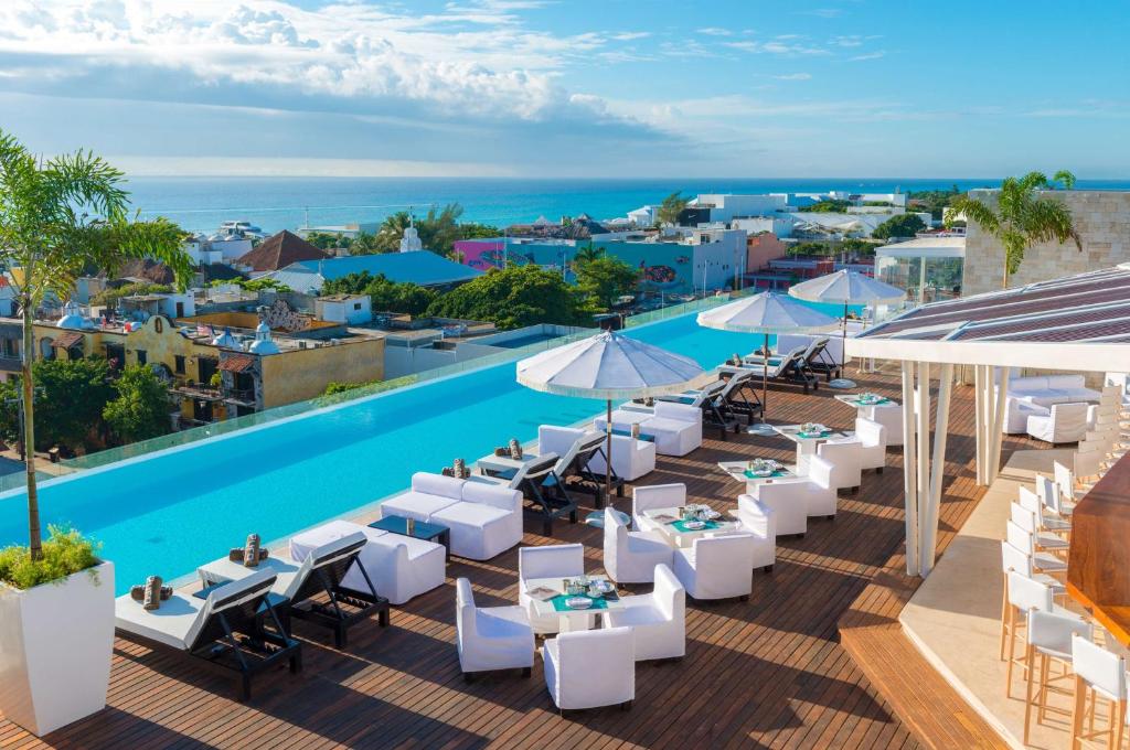 ein Bild eines Resorts mit einem Pool, Tischen und Stühlen in der Unterkunft The Fives Downtown Hotel & Residences, Curio Collection by Hilton in Playa del Carmen