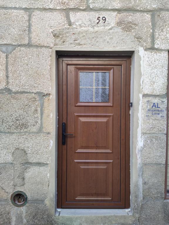 a wooden door in a stone wall with a window at Casa da Avó Ilda in Miranda do Douro