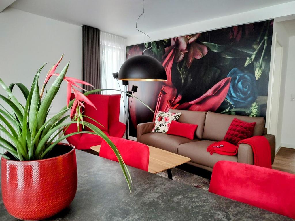 a living room with a couch and red chairs at Ferienwohnungen am Wasserfall in Bad Urach