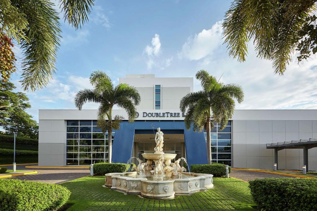 une fontaine en face d'un bâtiment avec des palmiers dans l'établissement Hilton DoubleTree by Hilton Managua, à Managua