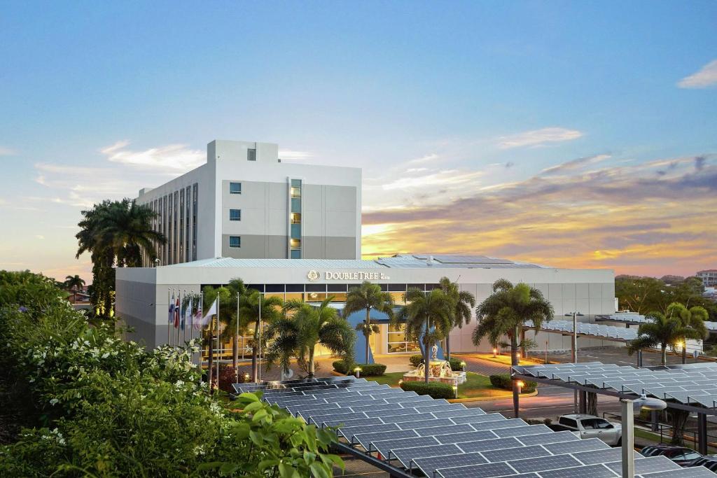a large white building with palm trees in front of it at DoubleTree by Hilton Managua in Managua