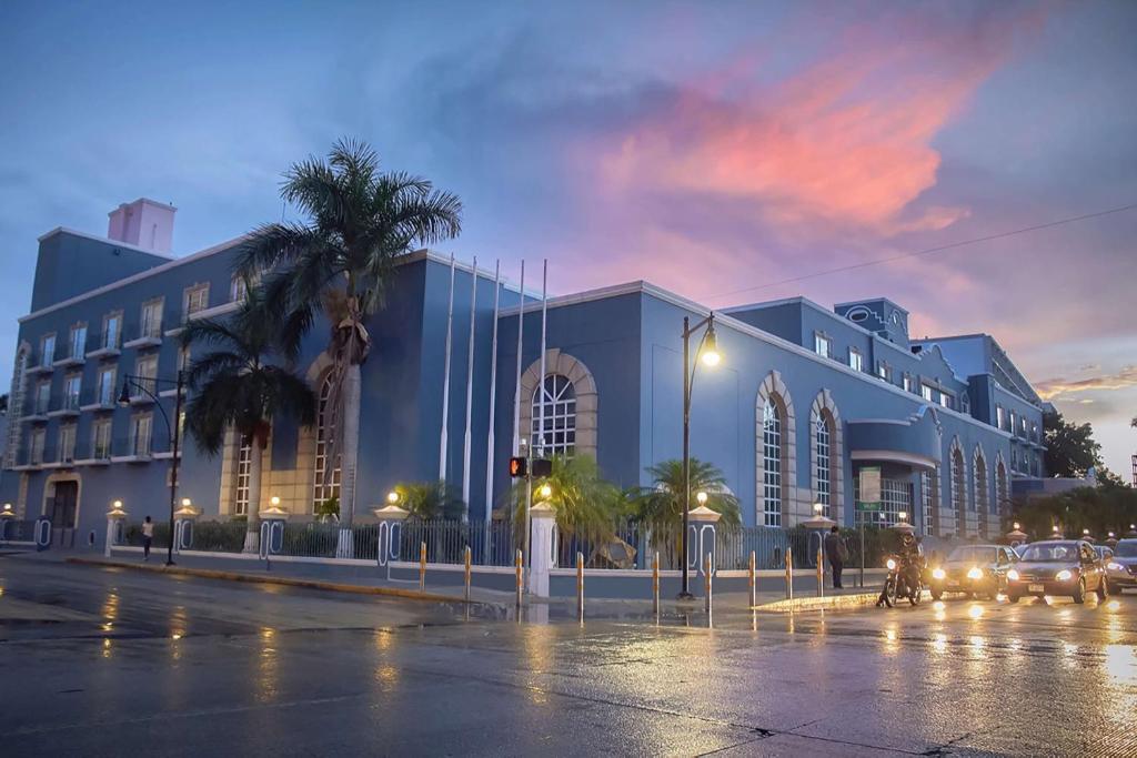 un gran edificio azul en una calle de la ciudad por la noche en Villa Mercedes Curio Collection By Hilton en Mérida