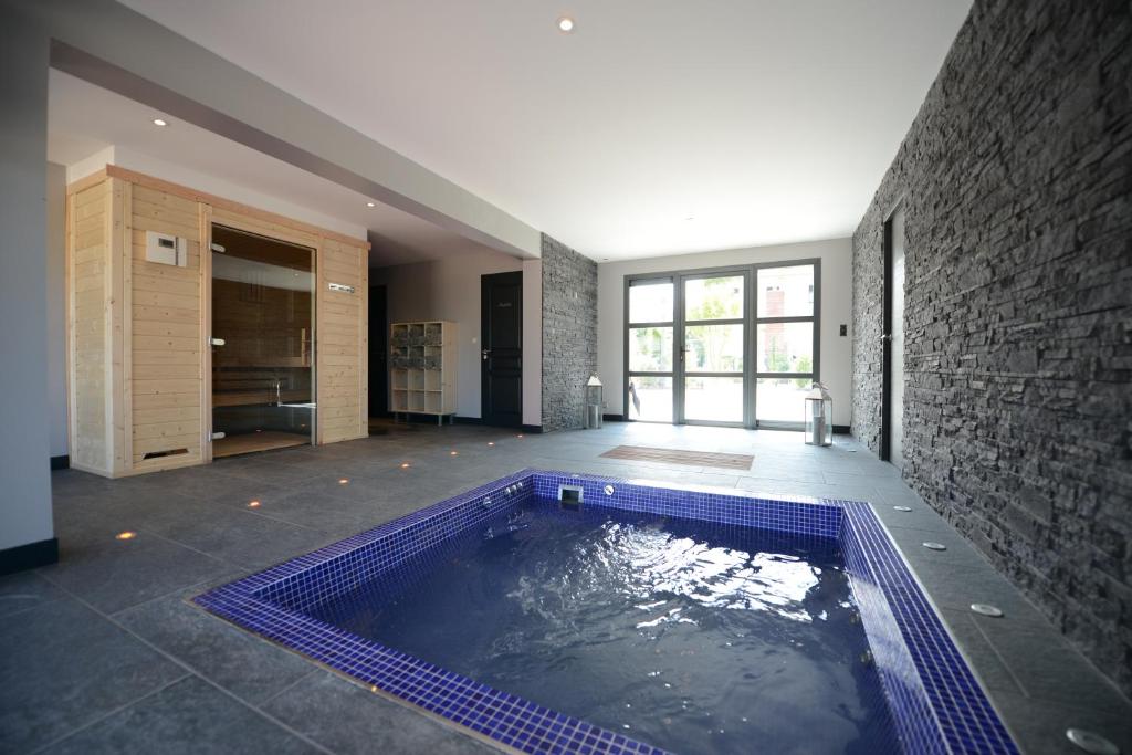 a swimming pool in a room with a stone wall at Hostellerie de la Renaissance - Teritoria in Argentan