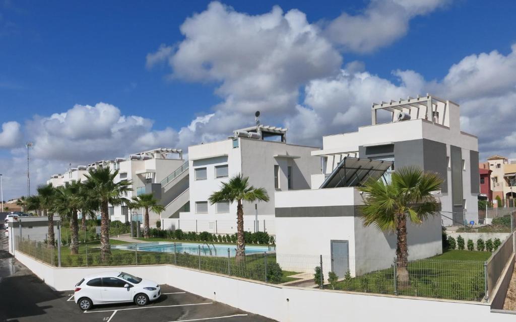 a white house with a car parked in front of it at Apartment Escorpiones in Torrevieja