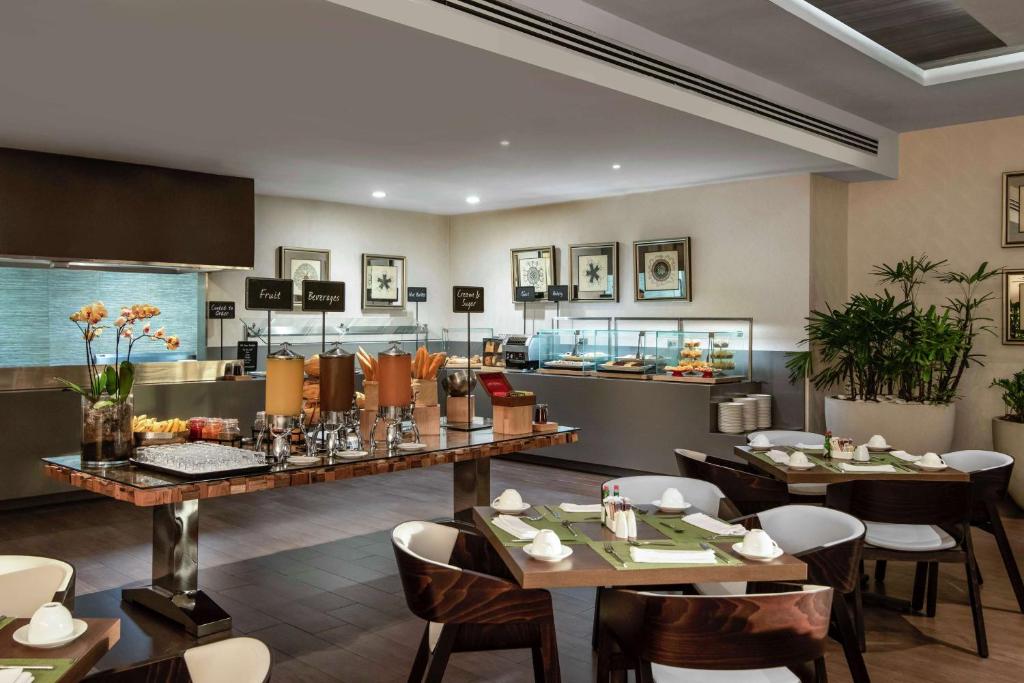 a restaurant with tables and chairs and a kitchen at Embassy Suites by Hilton Santo Domingo in Santo Domingo