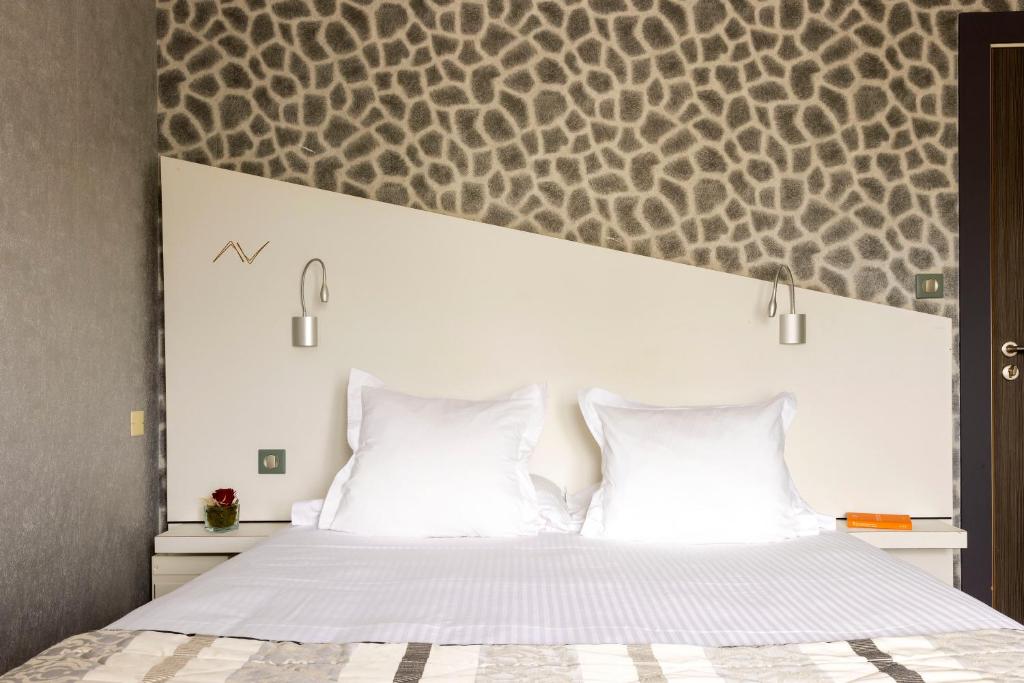 a bedroom with a large bed with two white pillows at Hostellerie de la Renaissance - Teritoria in Argentan