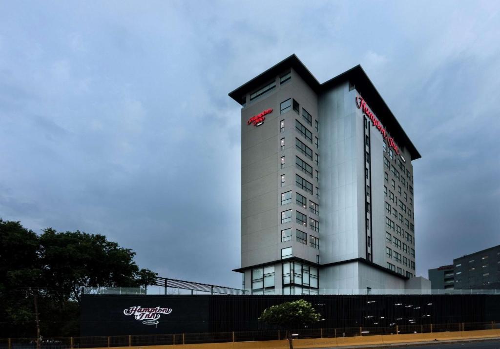 a tall white building with a red sign on it at Hampton Inn By Hilton San Luis Potosi in San Luis Potosí