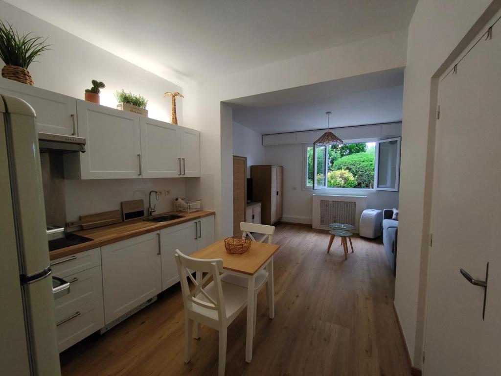 een keuken met witte kasten en een tafel met stoelen bij Studio Cap Martin in Roquebrune-Cap-Martin