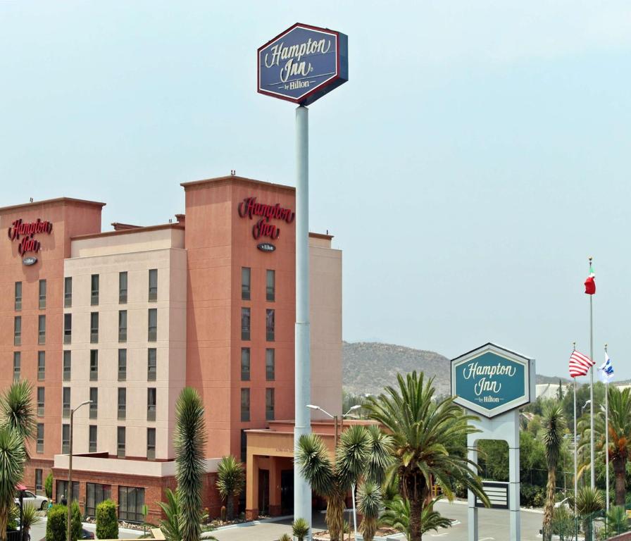 ein Schild für ein Hotel vor einem Gebäude in der Unterkunft Hampton by Hilton Saltillo Zona Aeropuerto in Saltillo