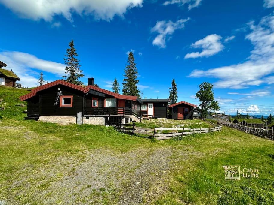 een huis op een grasheuvel met een hek bij Rustic cabin on Lake Sjusjøen with a lovely view in Ringsaker