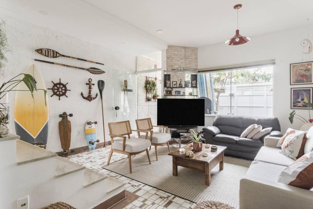 a living room with a couch and a tv at Suites Mar e Lua em casa compartilhada in Ubatuba