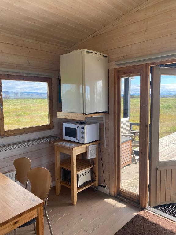 a room with a microwave and a table in a cabin at Log house with a view - Bjalki in Hella