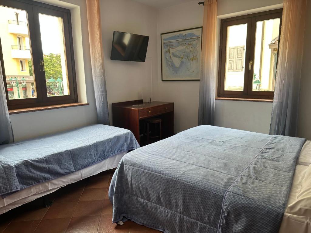 una camera con due letti e una TV a parete di Hotel Alla città di Trieste a Grado