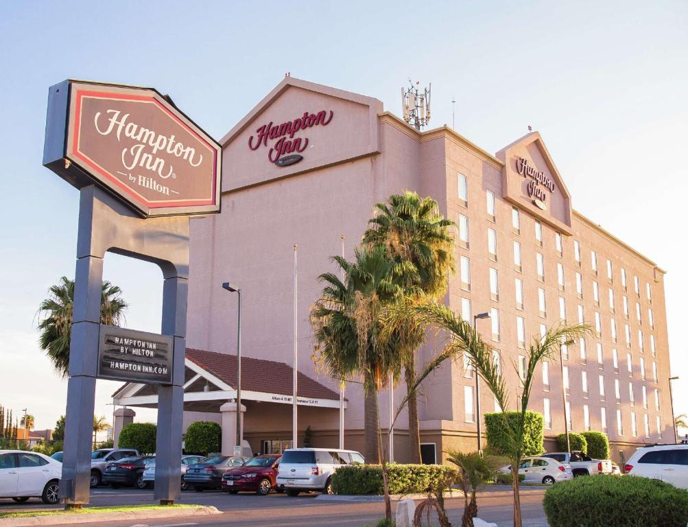 ein großes Gebäude mit Autos auf einem Parkplatz in der Unterkunft Hampton Inn Torreon Airport-Galerias in Torreón