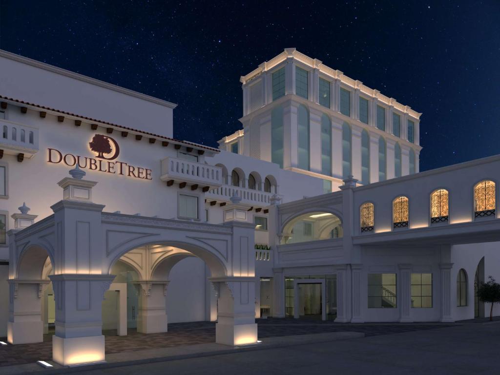 a large white building with a tall building in the background at Doubletree By Hilton Toluca in Toluca