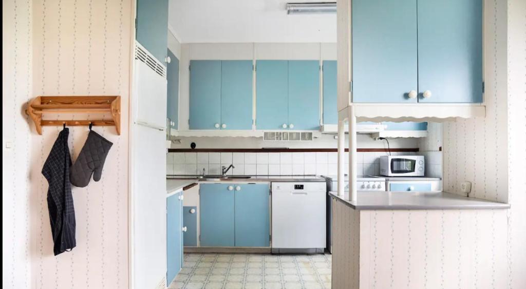 a kitchen with blue cabinets and a white refrigerator at By The Bay room in a shared villa in Gothenburg
