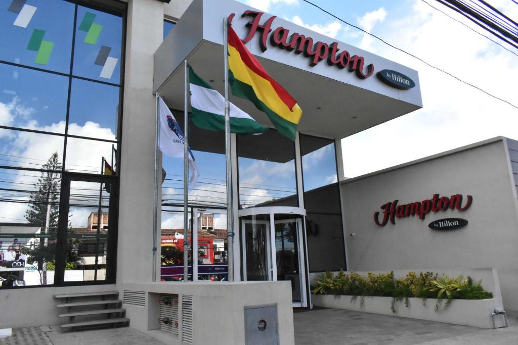 un restaurant avec drapeaux devant un bâtiment dans l'établissement Hampton by Hilton Santa Cruz, à Santa Cruz de la Sierra