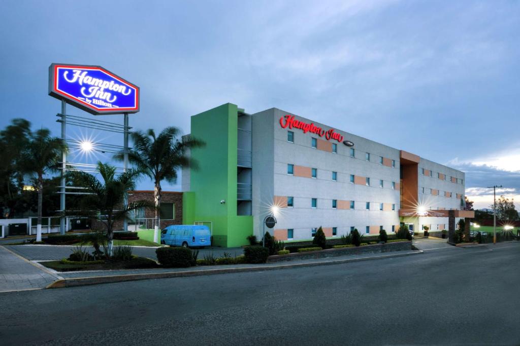 ein Hotel mit einem Schild vor einem Gebäude in der Unterkunft Hampton by Hilton San Juan del Rio in San Juan del Río