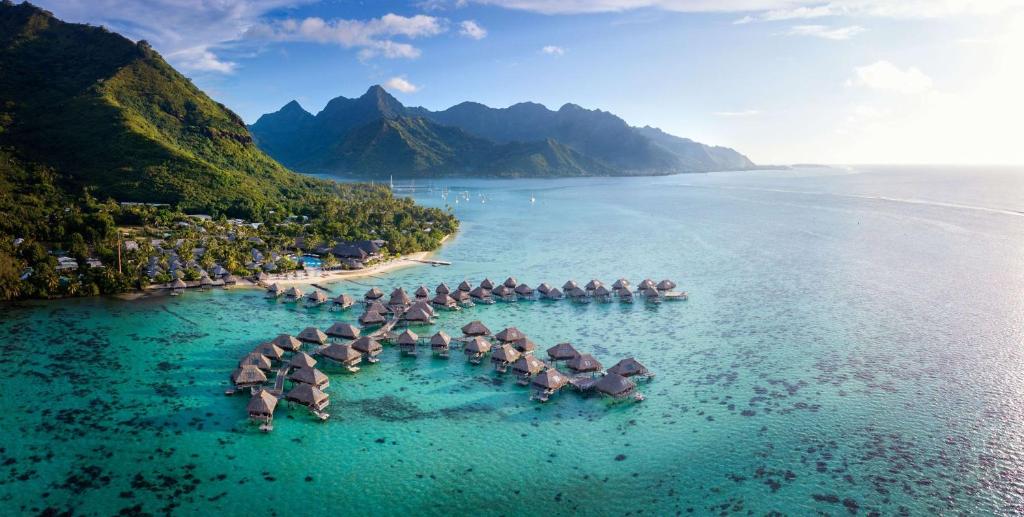 Hilton Moorea Lagoon Resort & Spa في بابيتوييْ: مجموعة من المظلات في الماء على الشاطئ