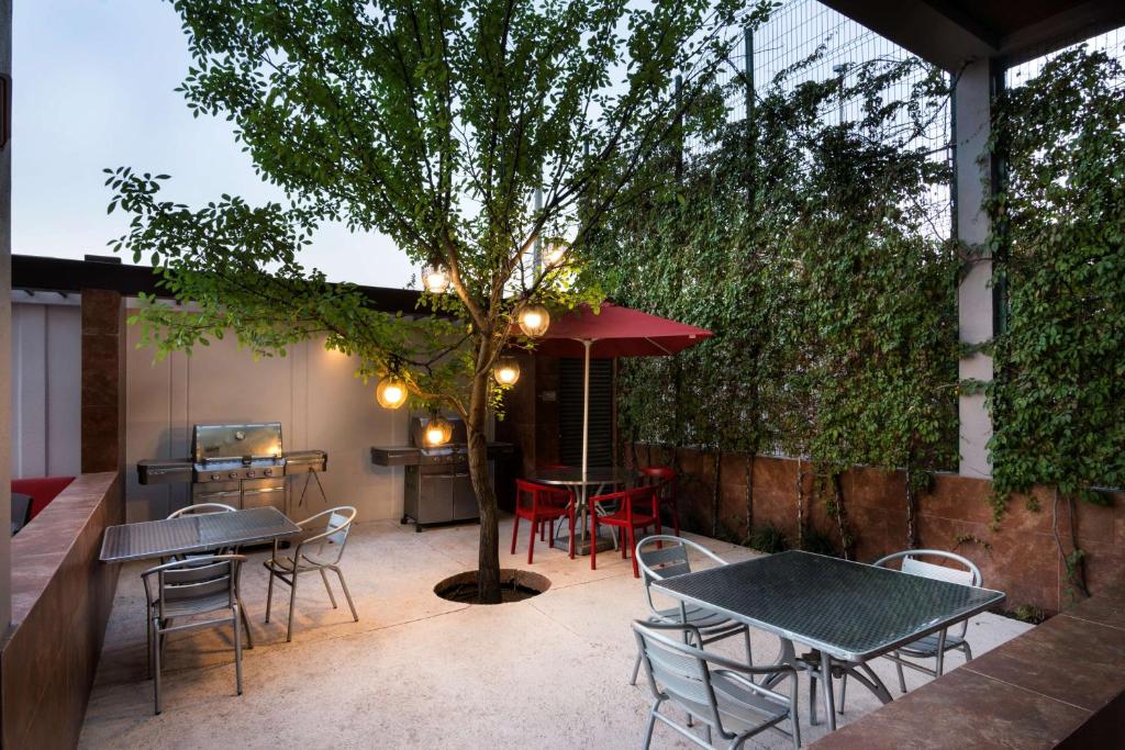 d'une terrasse avec des tables, des chaises et un arbre. dans l'établissement Homewood Suites by Hilton Queretaro, à Querétaro